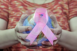 Woman hand holding pink breast cancer awareness ribbon.