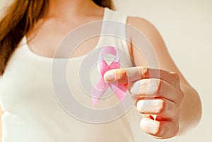 Woman hand holding pink ribbon, breast cancer awareness concept, healthcare and medicine