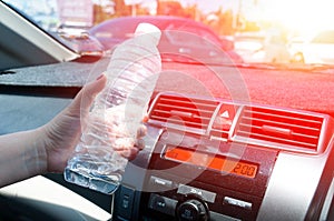 Woman hand holding a plastic bottle of water in car