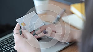 Woman hand holding plastic credit card and using laptop. Online shopping, internet banking concept.