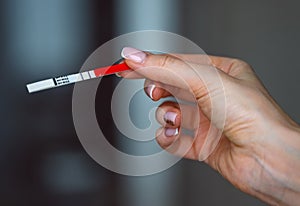 Woman hand holding positive pregnancy test with two lines on it. Pregnancy or fertility concept. High quality photo.