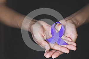 Woman Hand Holding Purple Ribbon, Domestic Violence Awareness Month October concept with deep purple awareness ribbon photo