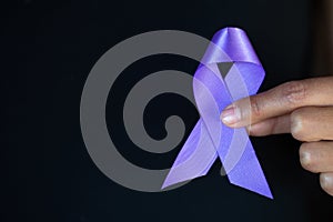 Woman Hand Holding Purple Ribbon, Domestic Violence Awareness Month October concept with deep purple awareness ribbon