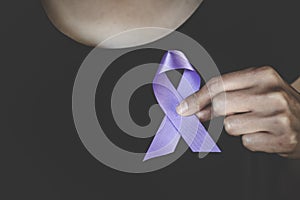 Woman Hand Holding Purple Ribbon, Domestic Violence Awareness Month October concept with deep purple awareness ribbon photo