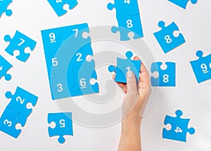 Woman hand holding  puzzle piece,  autism symbol.  Blue puzzle jigsaw with numbers on a white background. April 2, Autism World