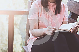 Woman hand holding and reading a book on the chair at house