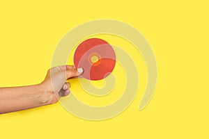 Woman hand holding a red CD on a yellow background