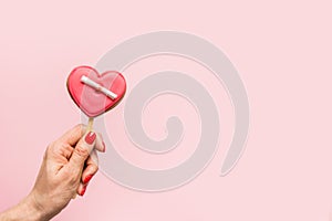 Woman hand holding red glazed cookies in shape of heart