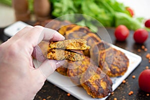 Woman hand holding red lentils patties. Close up of sliced patties or burger.