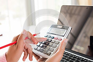 Woman hand holding red pencil and working with calculator
