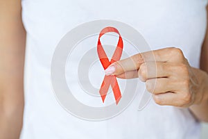 Woman hand holding red ribbon HIV, world AIDS day awareness ribbon.