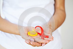 Woman hand holding red ribbon HIV, world AIDS day awareness ribbon.