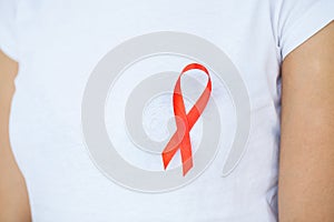 Woman hand holding red ribbon HIV, world AIDS day awareness ribbon.