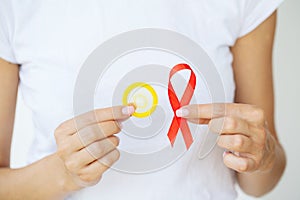 Woman hand holding red ribbon HIV world AIDS day awareness ribbon.