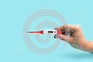 Woman hand holding a red and white medical thermometer