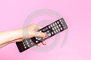 Woman hand holding remote control, on pink background