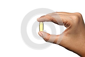 Woman hand holding single yellow Cod Liver Oil capsule on white background