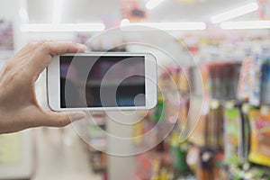 Woman hand holding smart phone in super market shopping