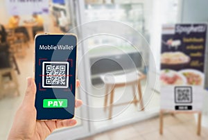 Woman hand holding smartphone with blurred shop background, with mobile wallet electronic and shopping online concept,with Qr code