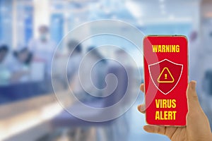 Woman hand holding smartphone in hand,with red screen and shield icon virus corona alert security,with blur hospital background,