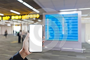 Woman hand holding smartphone mockup and blurred flight schedule background.