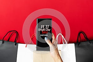 Woman hand holding smartphone with shopping bag, China 11.11 single day sale concept