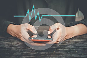 Woman hand holding smartphone with vital sign of heart beat background. Business technology health connection