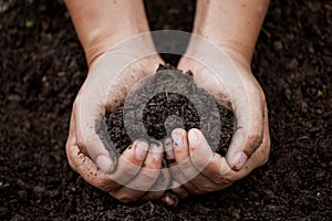 Woman hand holding soil in heart shape