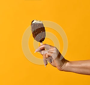 Woman hand holding strawberry ice cream popsicle on yellow pastel color