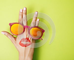 woman hand holding sunglasses on bright background, cosmetic summer vacation concept