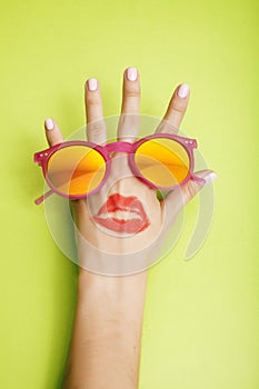 Woman hand holding sunglasses on bright background, cosmetic summer vacation concept close up