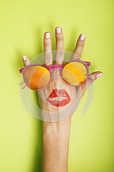 Woman hand holding sunglasses on bright background, cosmetic summer vacation concept close up