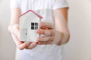 Woman hand holding toy model house  on white background. Real estate mortgage property insurance dream home