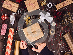 Woman hand holding twine rope with scissors for cutting and packaging christmas gift box