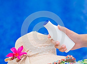 Woman hand holding UV sunscreen bottle with summer hat