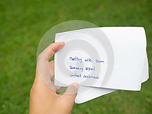 Woman hand holding white paper written day business plan. Meeting team, summary report and meet customers in green background