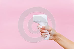 Woman hand holding white thermometer on pink background