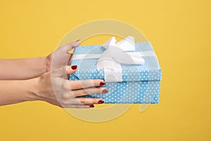 Woman hand holding wrapped blue gift box with white stripe, delivery of present on holidays. photo
