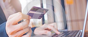 Woman hand holds a blue credit card.And are using a laptop computer.Web banner