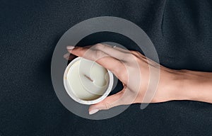 Woman hand holds a decorative scented candle on a black background
