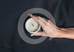 Woman hand holds a decorative scented candle on a black background