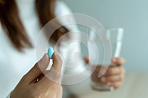 The woman hand holds a pill and a glass of water. The patient is about to take the medicine. Taking care of the sick body using an