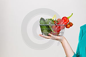 Woman hand holds shopping basket with vegetables