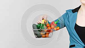 Woman hand holds shopping basket with vegetables