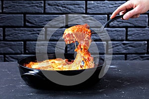 Woman hand holds spatula with Italian cannelloni