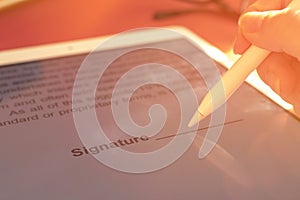 Woman hand holds stylus pencil and puts an electronic signature in contract on the tablet, selective focus