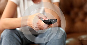 Woman hand holds TV remote control and presses buttons