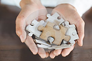 The woman hand holds a wooden jigsaw, solutions and strategy Concept