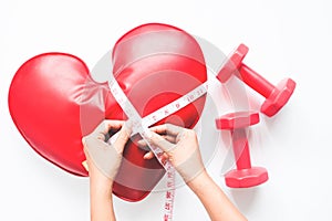 Woman hand holing measuring-tape on heart and dumbbell on white background, Healthy diet