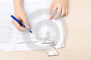 Woman hand and home key. Signed contract and keys of the property with documents. Concept for real estate business